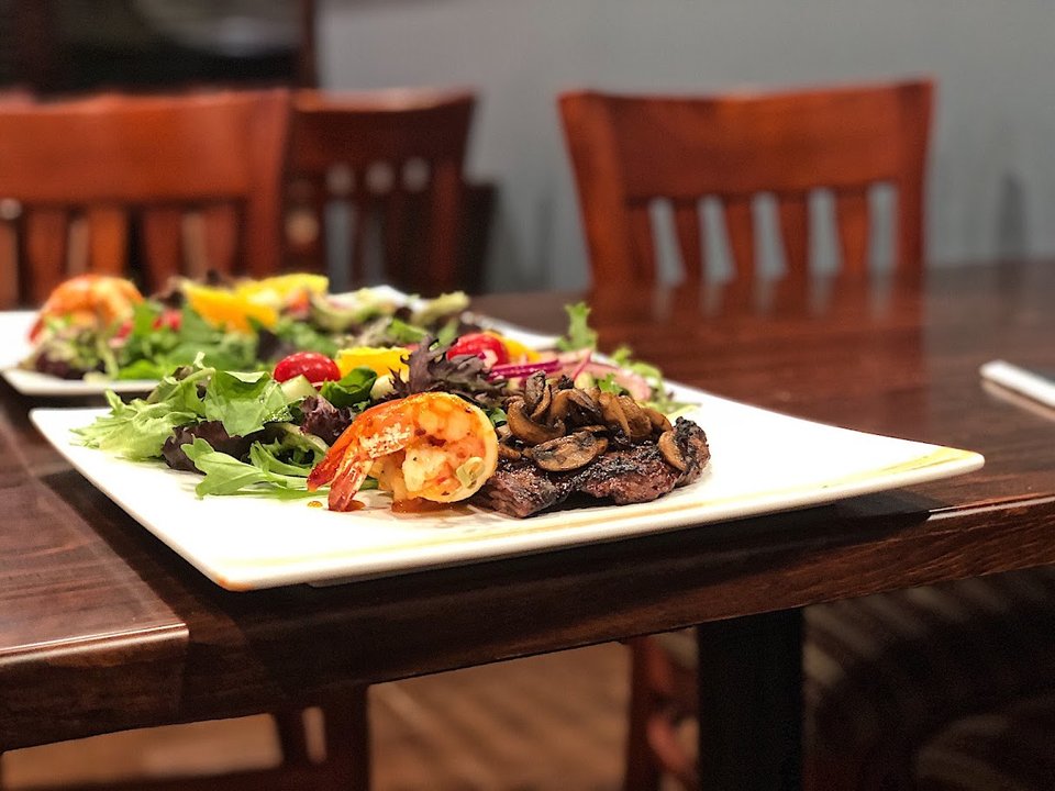 A plated steak dish beside restaurant drinks.